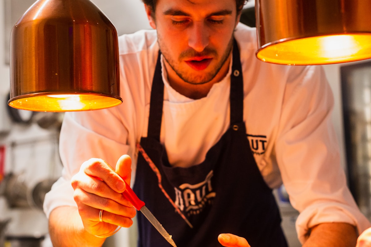 Chef plating a dish under the pass lights